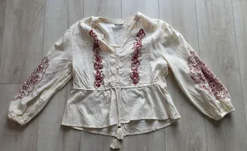 Cream cotton blouse with burgundy embroidery, laid flat